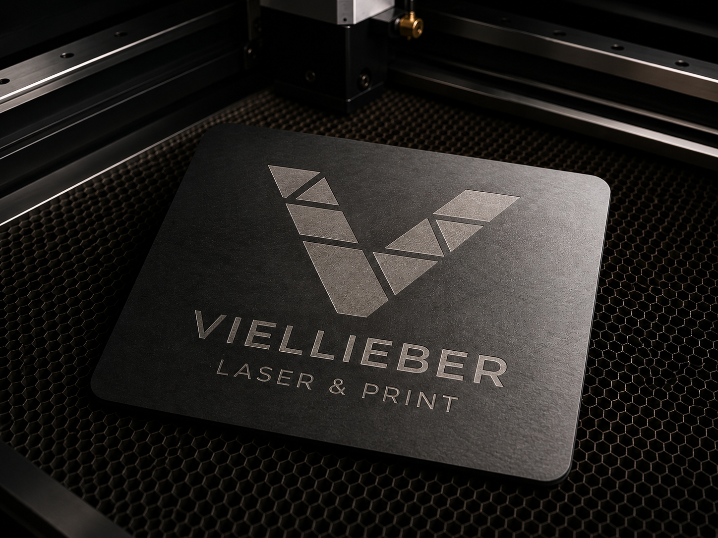 Lasergravierte Aluminiumplatte mit Viellieber-Logo im Arbeitsbereich des Lasercutters für eine Laserbeschriftung nach Maß.
